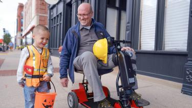 child walking with man on scooter