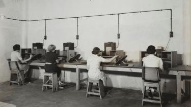 individuals sitting on chairs operating old fashioned computers